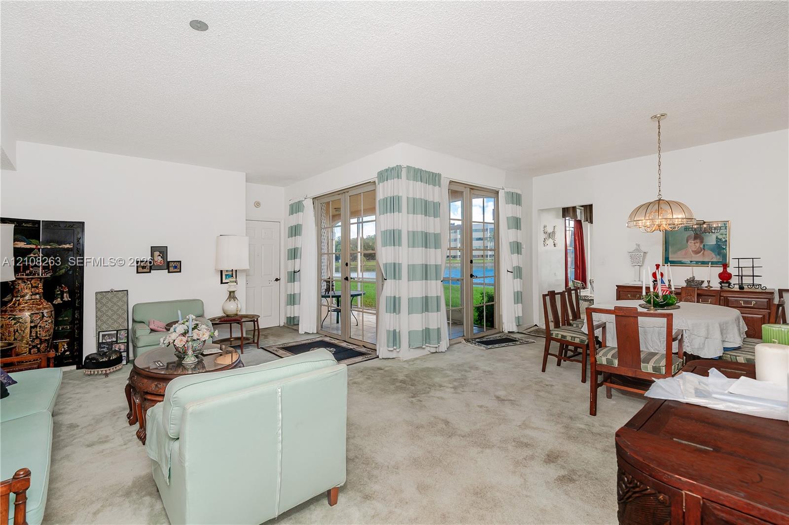 Living area featuring carpeted flooring, two sets of glass-paned doors, and a hanging pendant light fixture