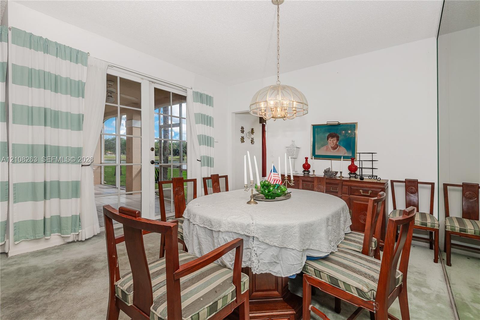 Dining area featuring glass-paned French doors, a metallic dome chandelier, and a full-length wall mirror
