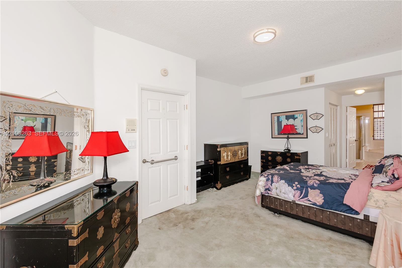 Room featuring neutral wall-to-wall carpeting, a six-panel interior door, and flush-mount ceiling lighting