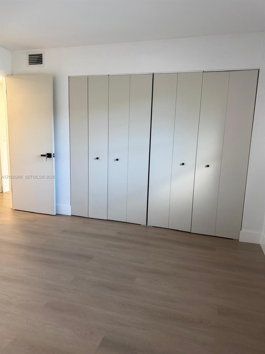 Wood-finish flooring, full-wall built-in cabinetry with neutral panel doors, matte black hardware, and crisp white wall finishes