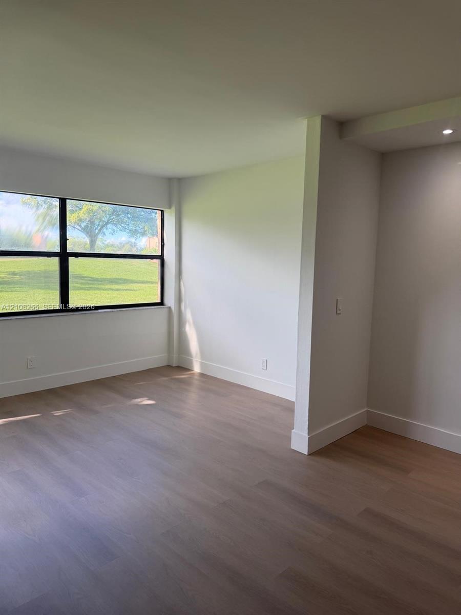 Room featuring wood-finish flooring, neutral walls, and a large horizontal window with black framing