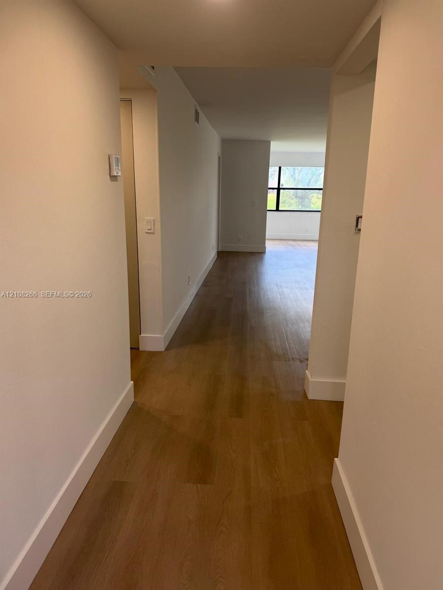 Interior corridor featuring wood-finish flooring, neutral walls, and a multi-pane window