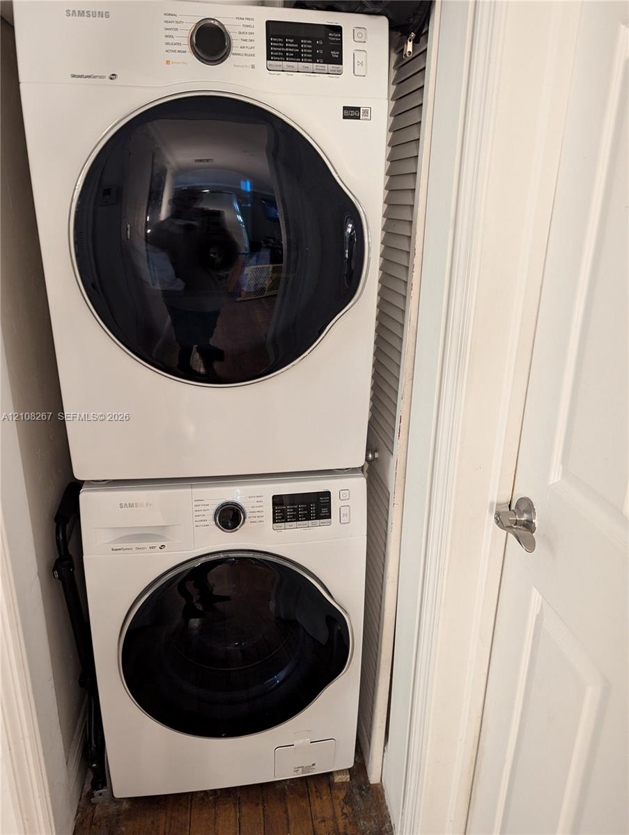 Stacked white front-load washer and dryer unit, louvered closet door, and interior door with brushed nickel hardware