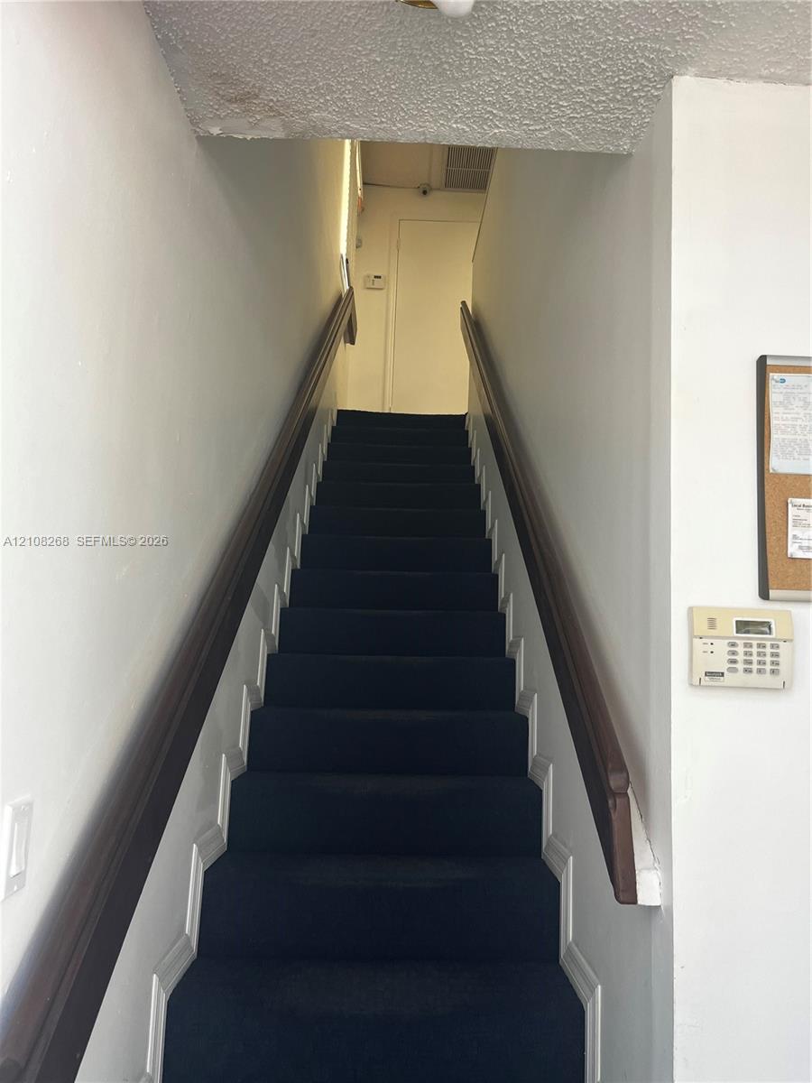 Staircase featuring dark carpeting and dual wooden handrails