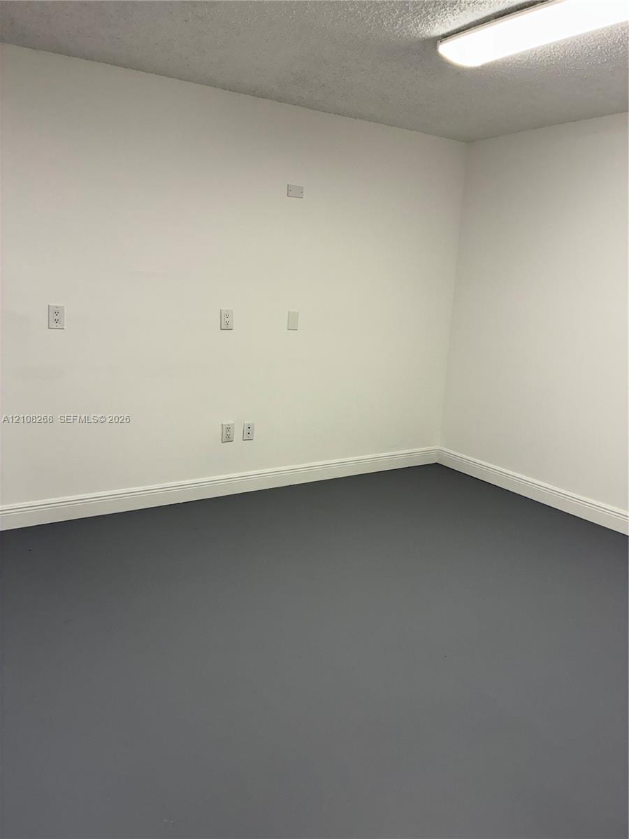 Interior room featuring gray painted flooring, white walls, and a ceiling-mounted light fixture