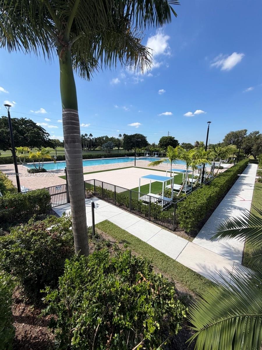Swimming pool with concrete decking, surrounding black metal fencing, synthetic turf accents, and perimeter landscaping Swimming pool with concrete decking, surrounding black metal fencing, synthetic turf accents, and perimeter landscaping