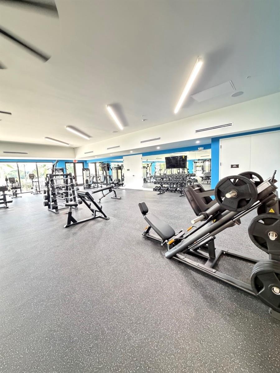 Fitness center featuring durable rubberized flooring, linear LED lighting, and expansive wall-to-wall mirrors