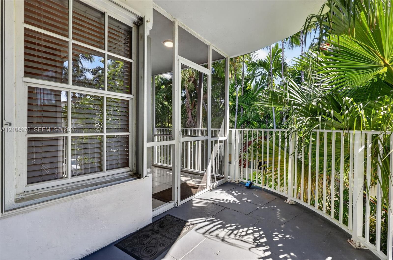 Covered balcony featuring tile flooring, white metal railing, and a screen enclosure