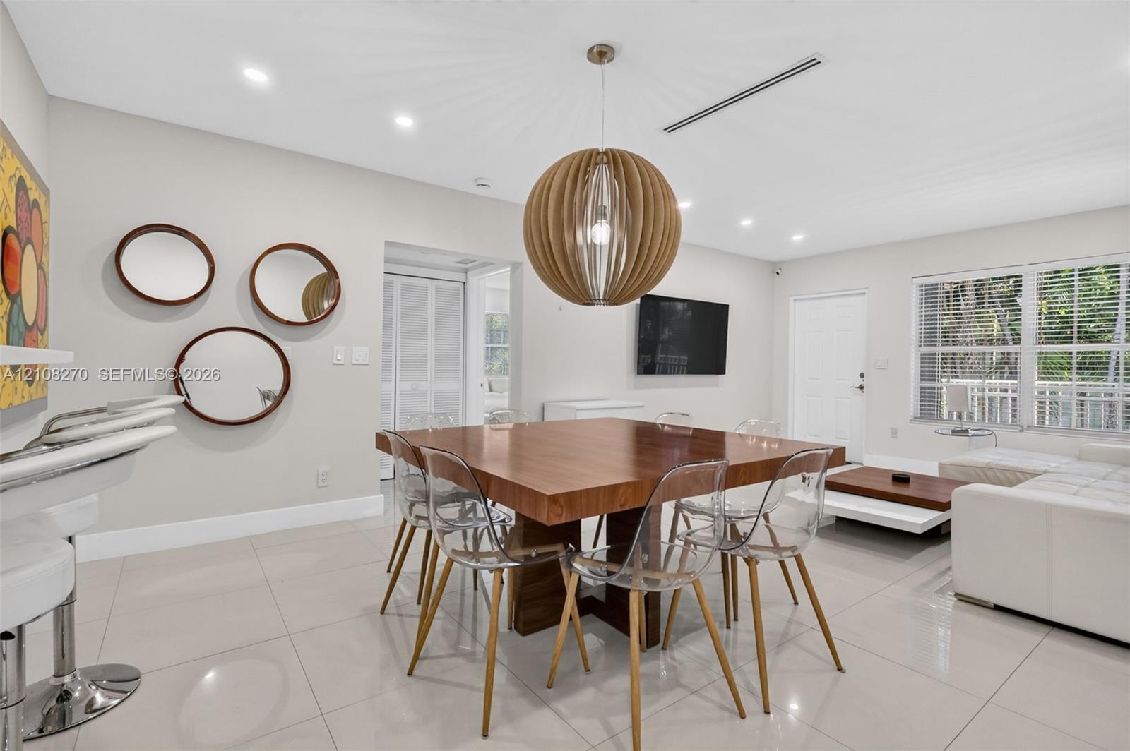Large-format neutral floor tiling, recessed lighting, and a prominent spherical pendant light fixture
