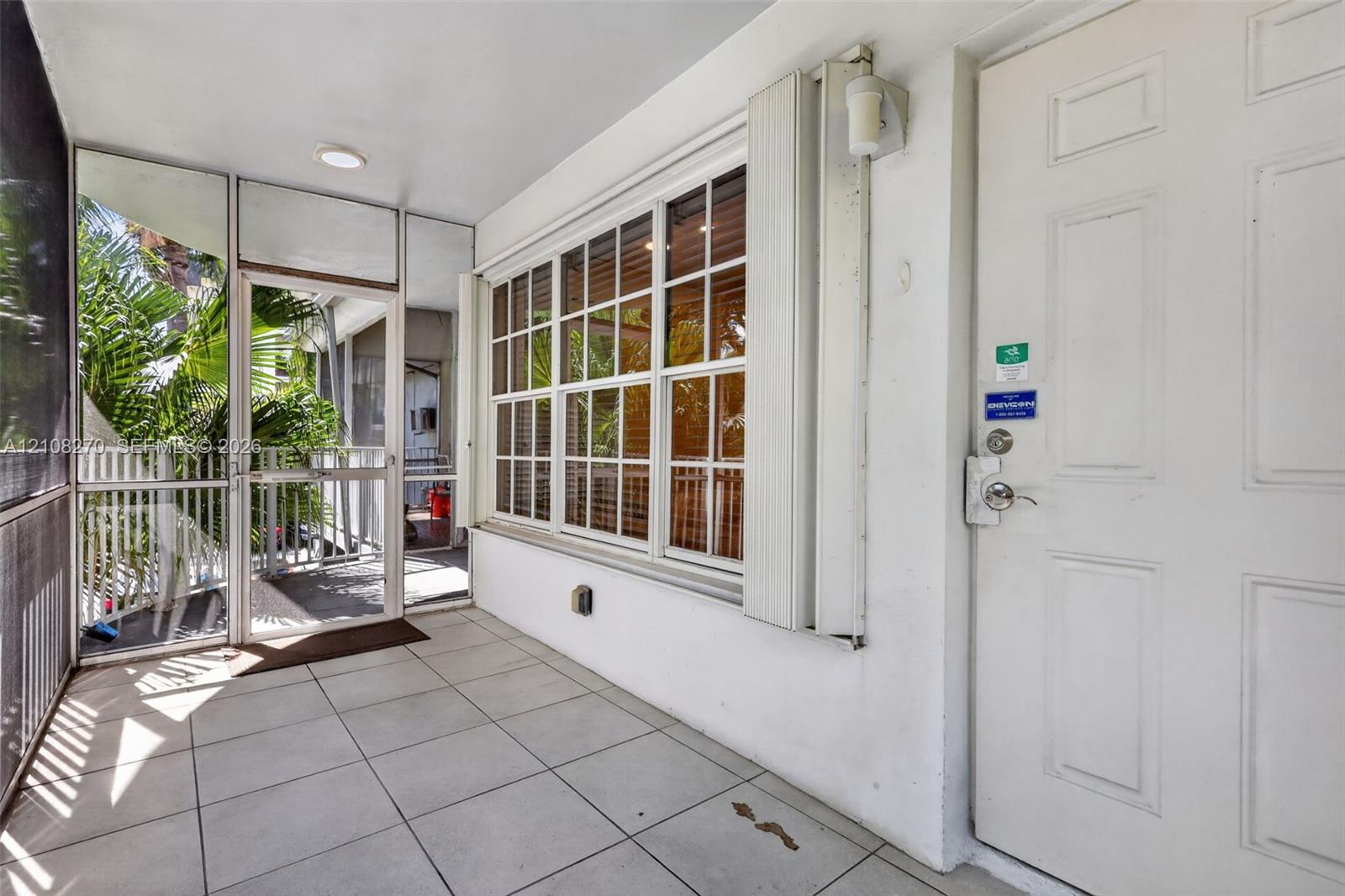 Screened-in porch featuring tiled flooring, a multi-pane window with aluminum framing, and an exterior door