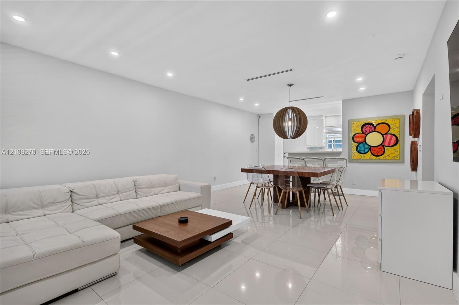 Open-concept interior featuring large-format tile flooring, recessed lighting, and a spherical wood-slat pendant fixture Open-concept interior featuring large-format tile flooring, recessed lighting, and a spherical wood-slat pendant fixture