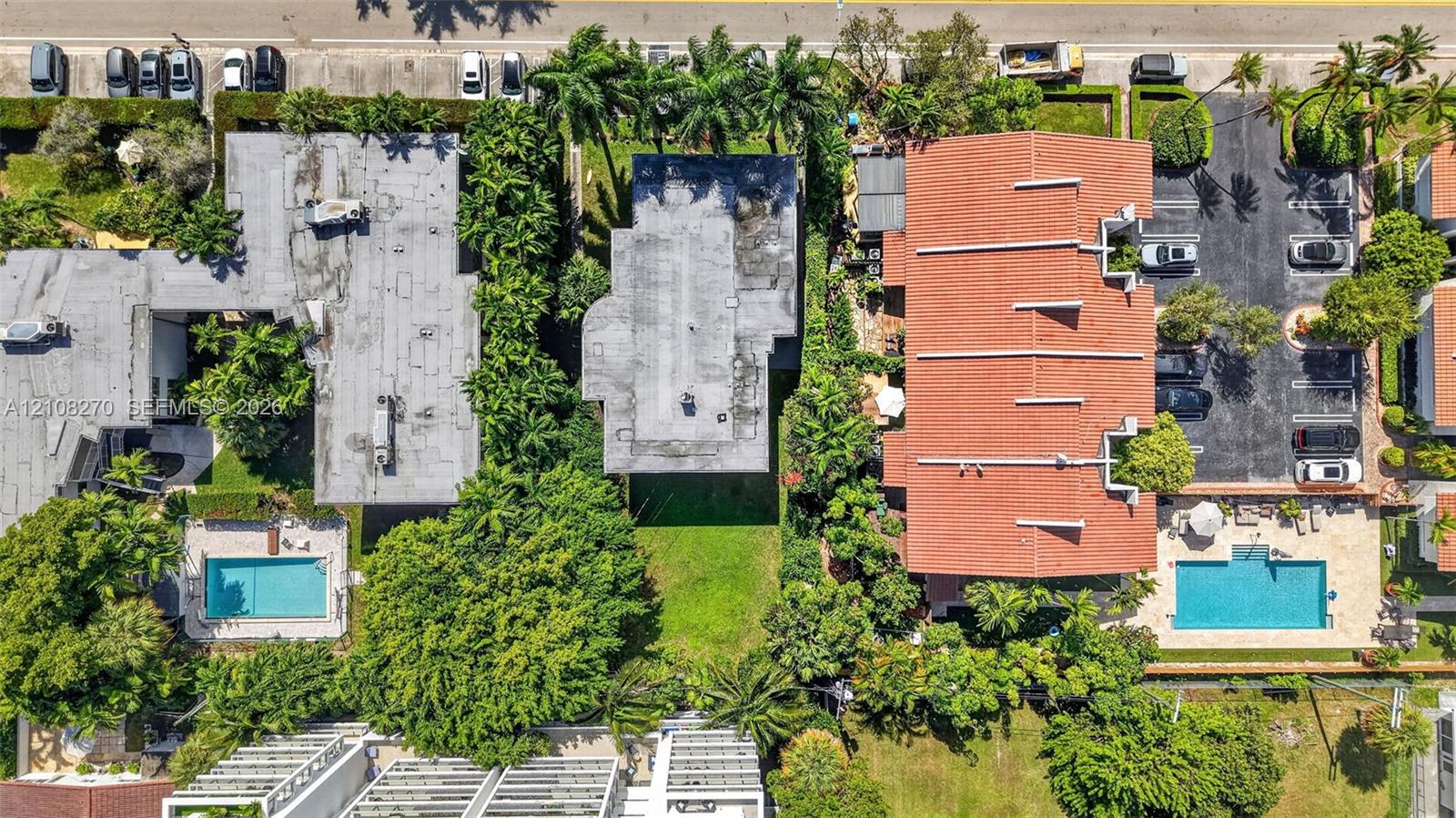 Aerial perspective showcasing a parcel of land with established green space, mature canopy trees, lush landscaping, and integrated paved parking