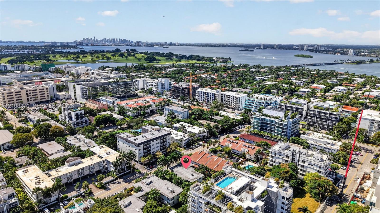 Aerial perspective of coastal neighborhood featuring mature palm trees and proximity to open water