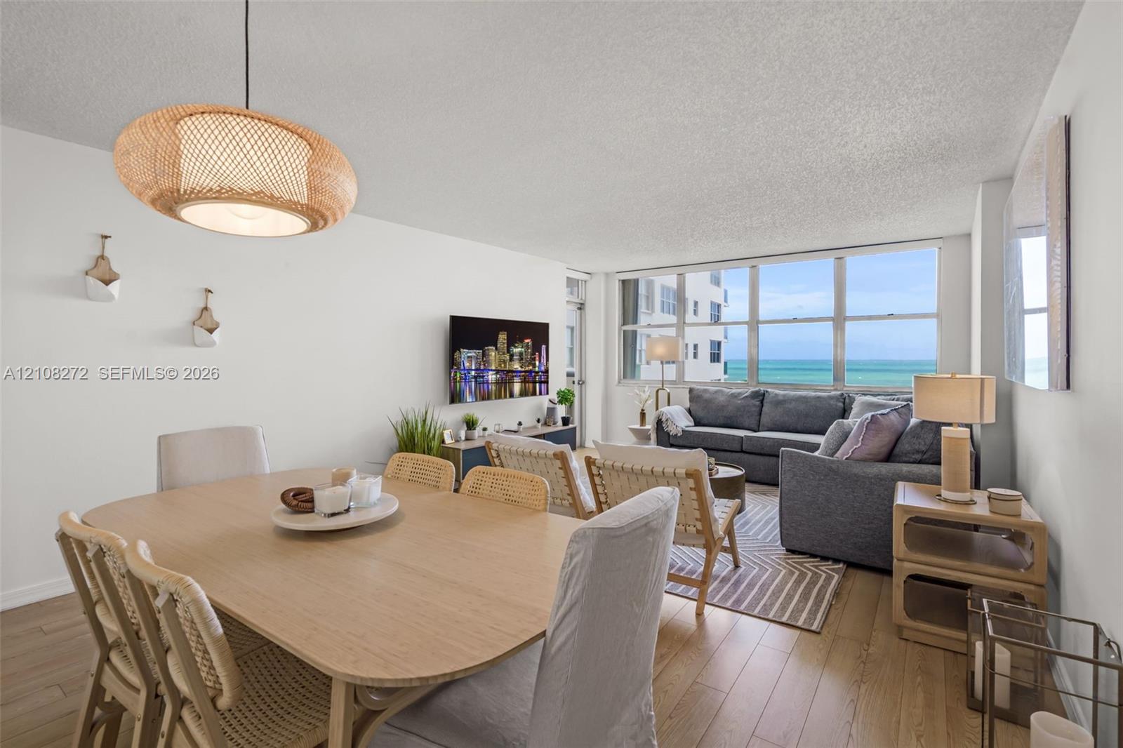 Open-concept living space featuring wood-finish flooring, floor-to-ceiling windows, and a woven pendant light fixture