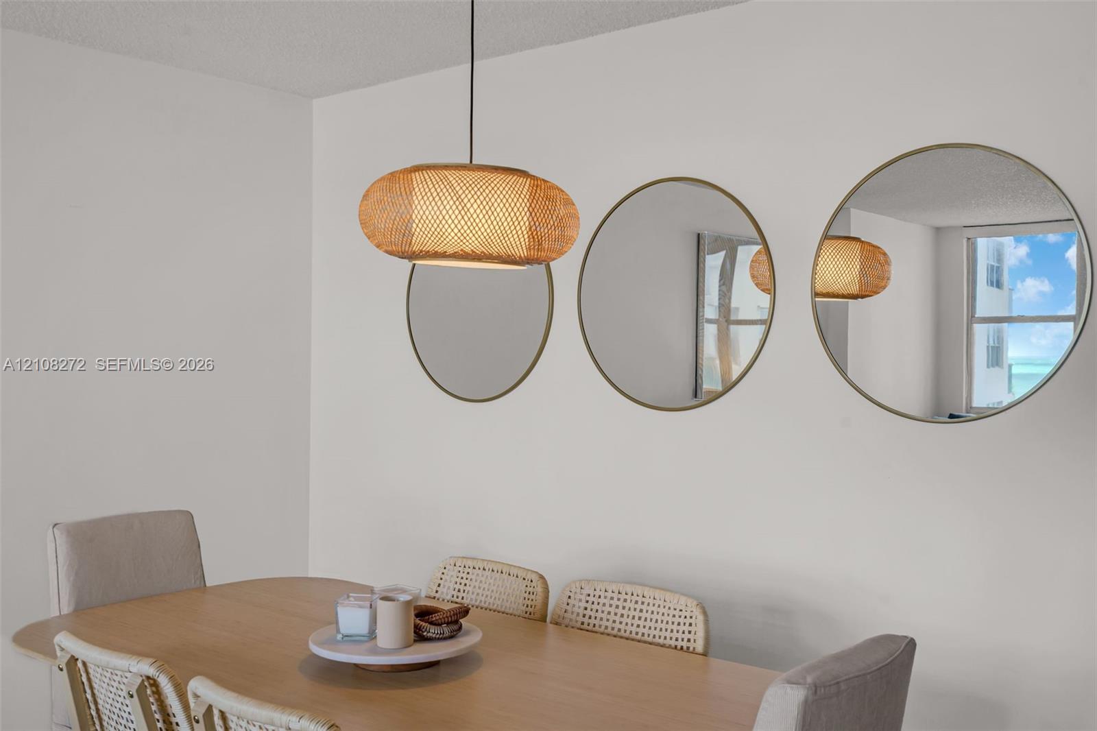 Woven rattan pendant light fixture and three circular wall-mounted mirrors with metallic frames