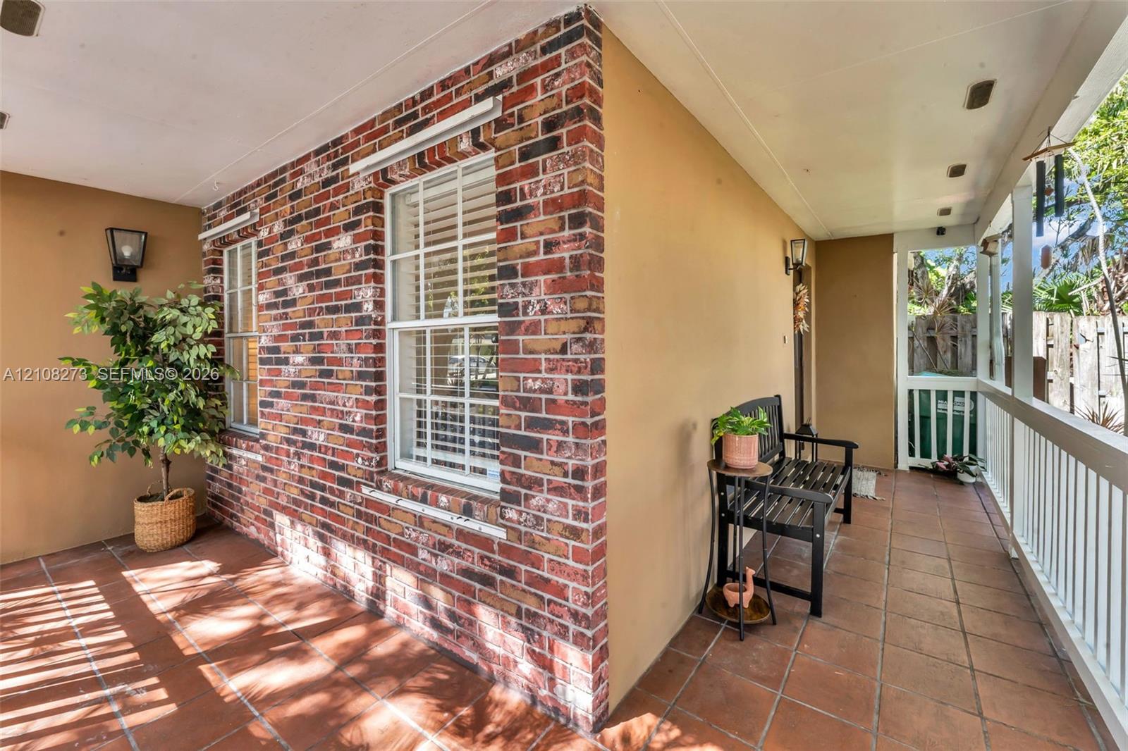 Covered porch featuring multi-tonal brick masonry, ceramic tile flooring, and white railing enclosures
