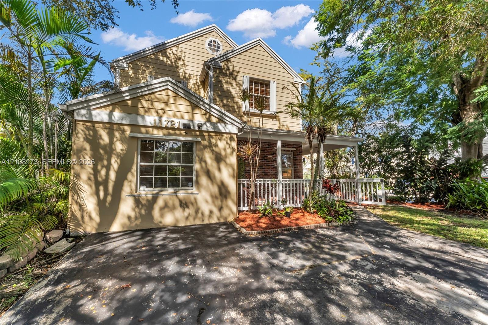 Two-story residence featuring horizontal siding, a brick facade accent, an integrated front porch with white railing, and an asphalt driveway