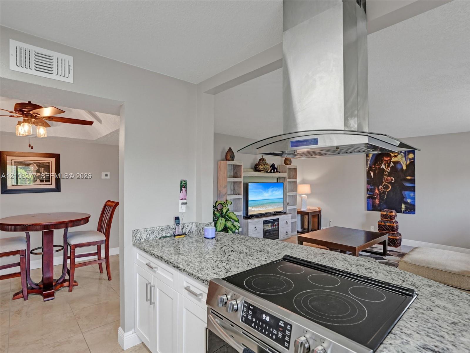 Kitchen featuring a stone countertop peninsula, stainless steel slide-in electric range, and a ceiling-mounted stainless steel chimney-style range hood