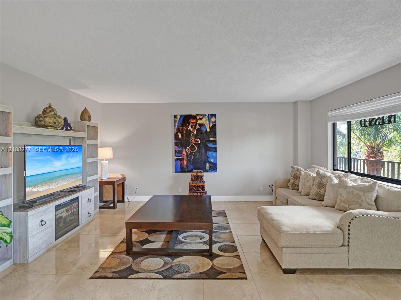 Living area featuring large-format tile flooring, light-toned built-in cabinetry, and a picture window