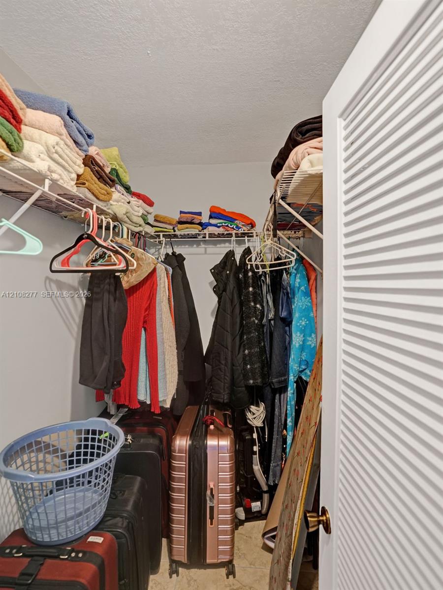 Storage space featuring ventilated wire shelving, neutral wall tones, and a louvered entry door with metallic hardware