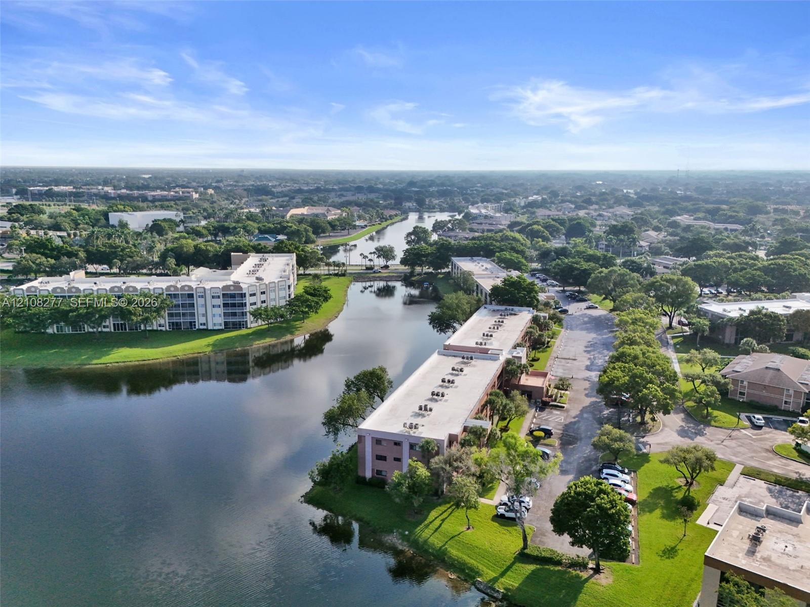 Aerial perspective featuring waterfront residential buildings, mature trees, and landscaped green space