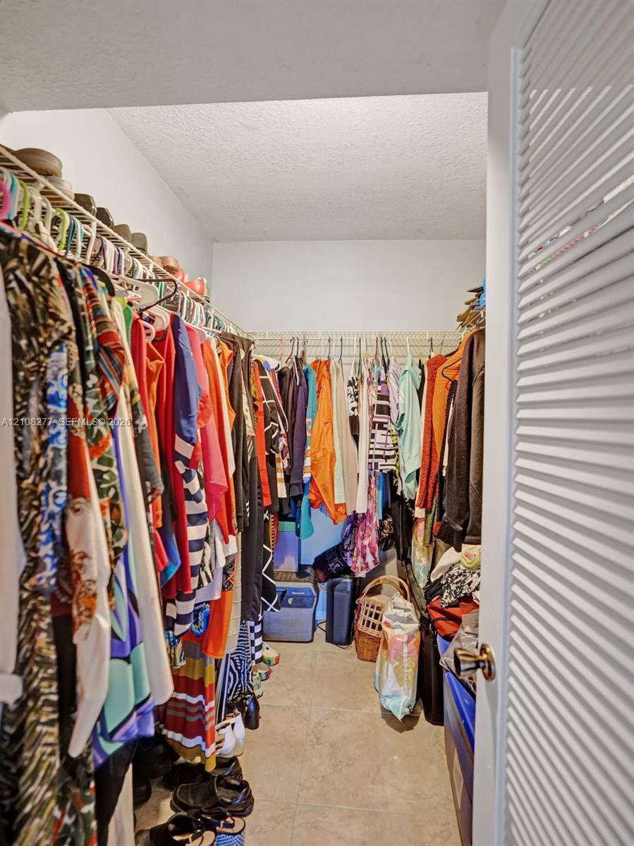 Walk-in closet featuring floor-to-ceiling metal wire shelving and neutral tile flooring