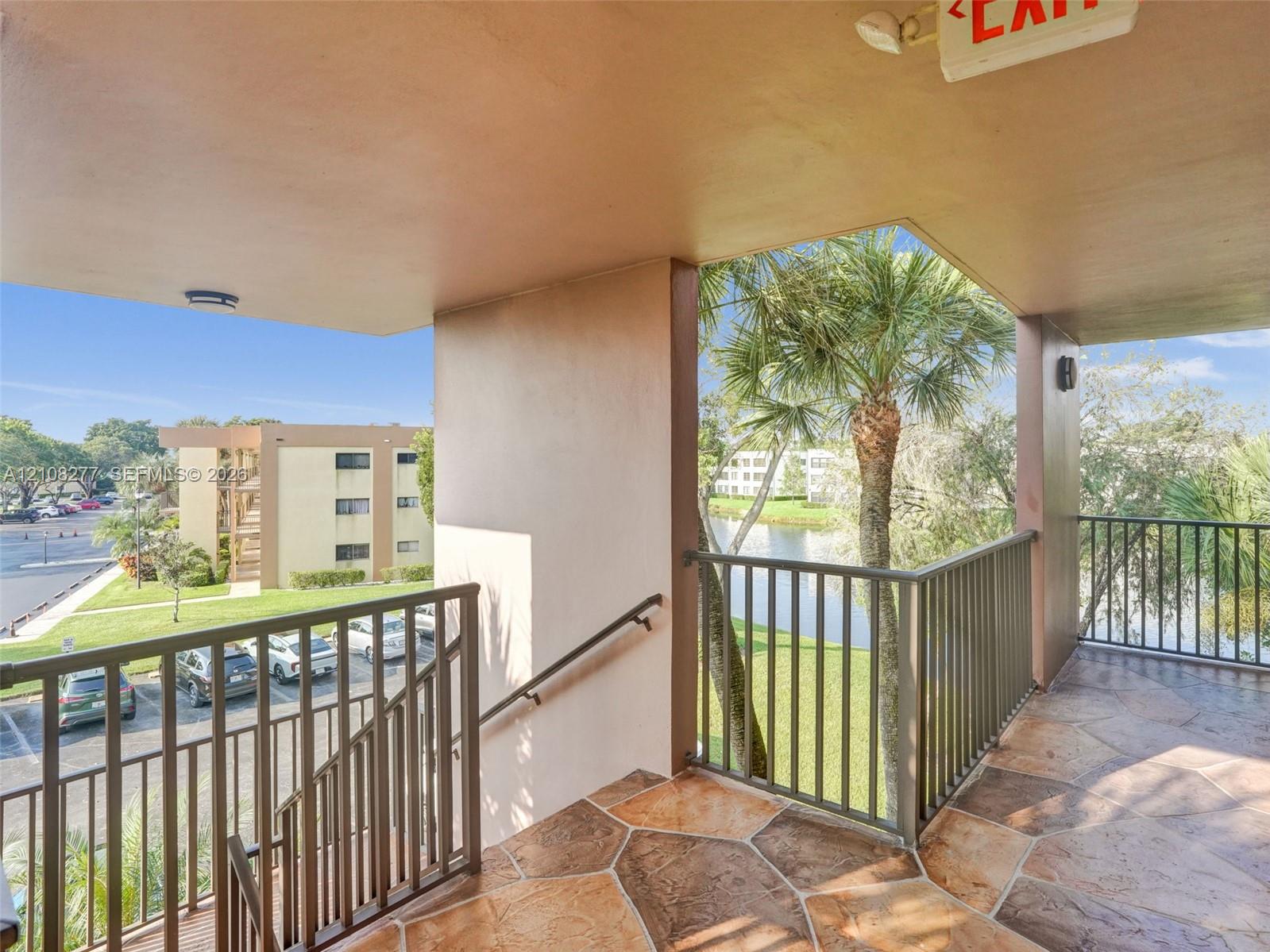 Covered exterior landing with stone-pattern flooring, metal railings, and a wall-mounted handrail