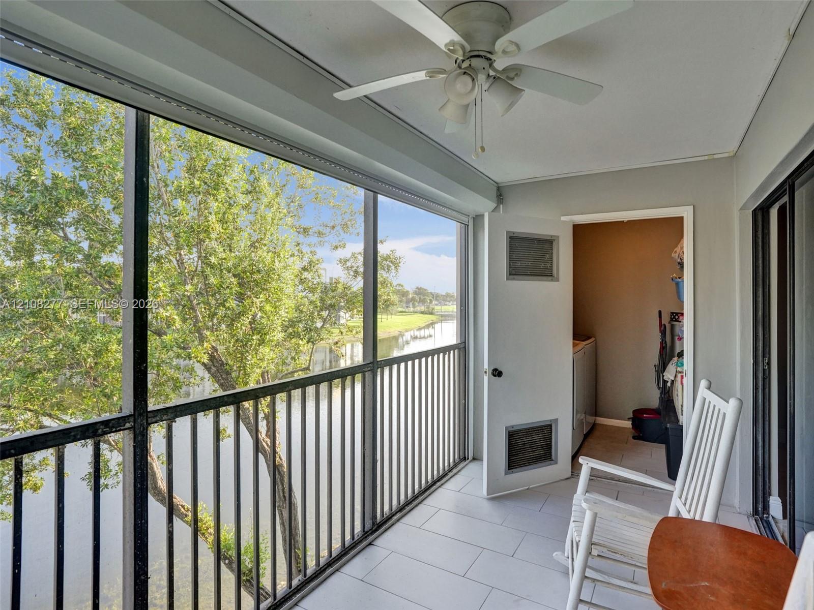 Screened-in balcony featuring tile flooring, a ceiling fan with integrated lighting, and a metal railing