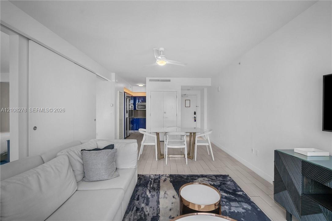 Open-concept interior featuring wood-finish tile flooring, ceiling fan, and smooth-finish walls
