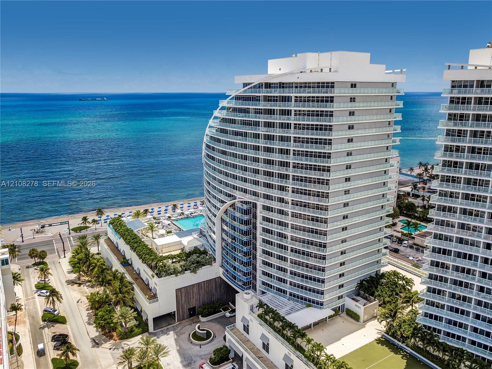 High-rise architectural design with glass-railing balconies, coastal waterfront location, and integrated multi-level terraced landscaping