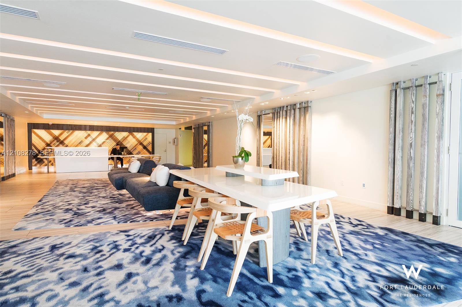 Tray ceiling with integrated linear lighting, chevron-patterned wood accent wall, and wood-finish flooring