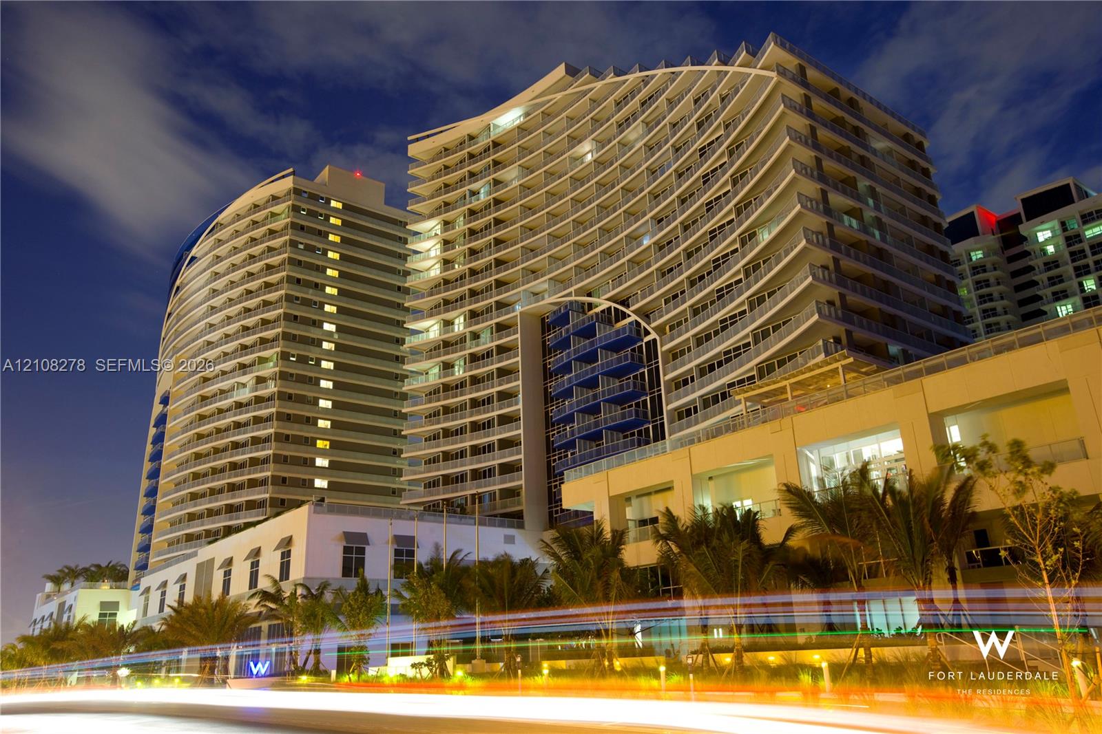 Modern high-rise architectural facade featuring undulating balconies, expansive glass panels, and integrated recessed lighting