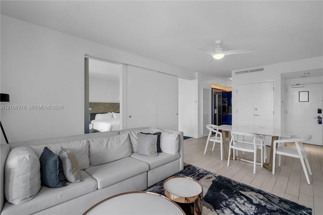 Open-concept interior featuring wood-finish flooring, white sliding partition doors, and a ceiling-mounted light fixture with integrated fan