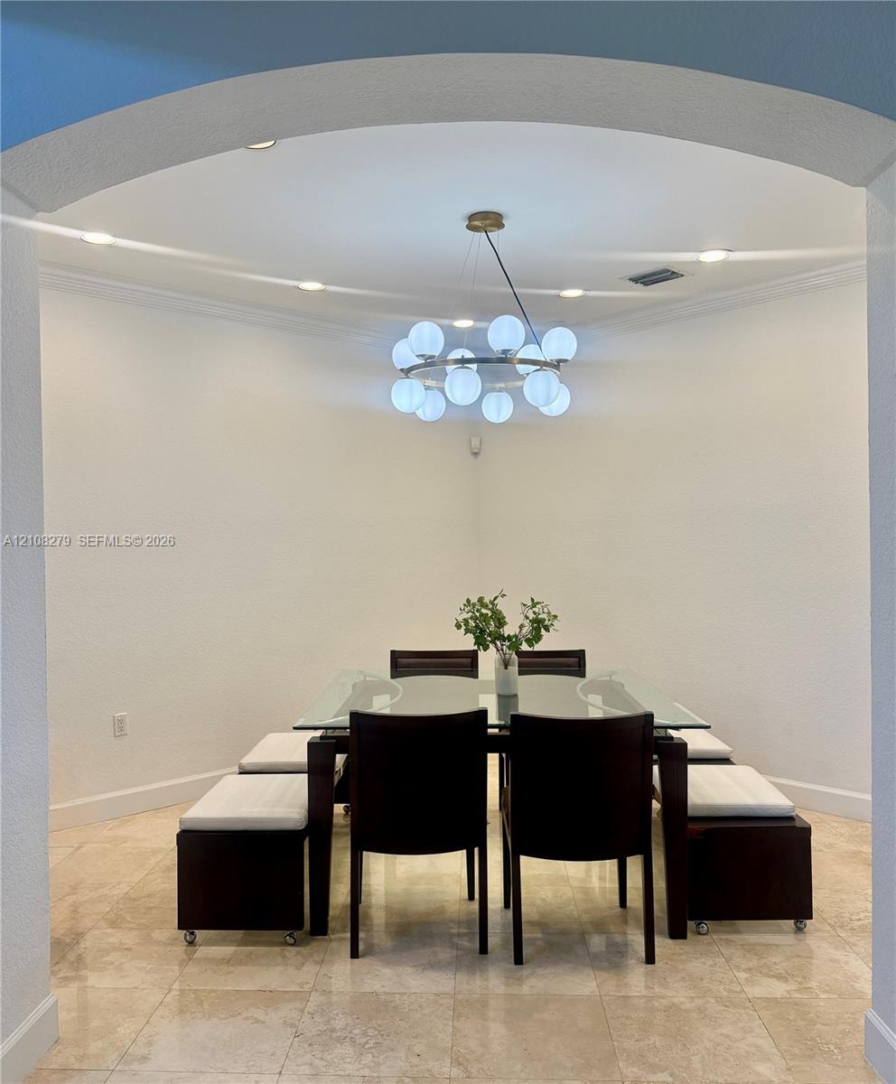 Arched entryway featuring polished stone flooring, recessed lighting, and a contemporary multi-globe chandelier