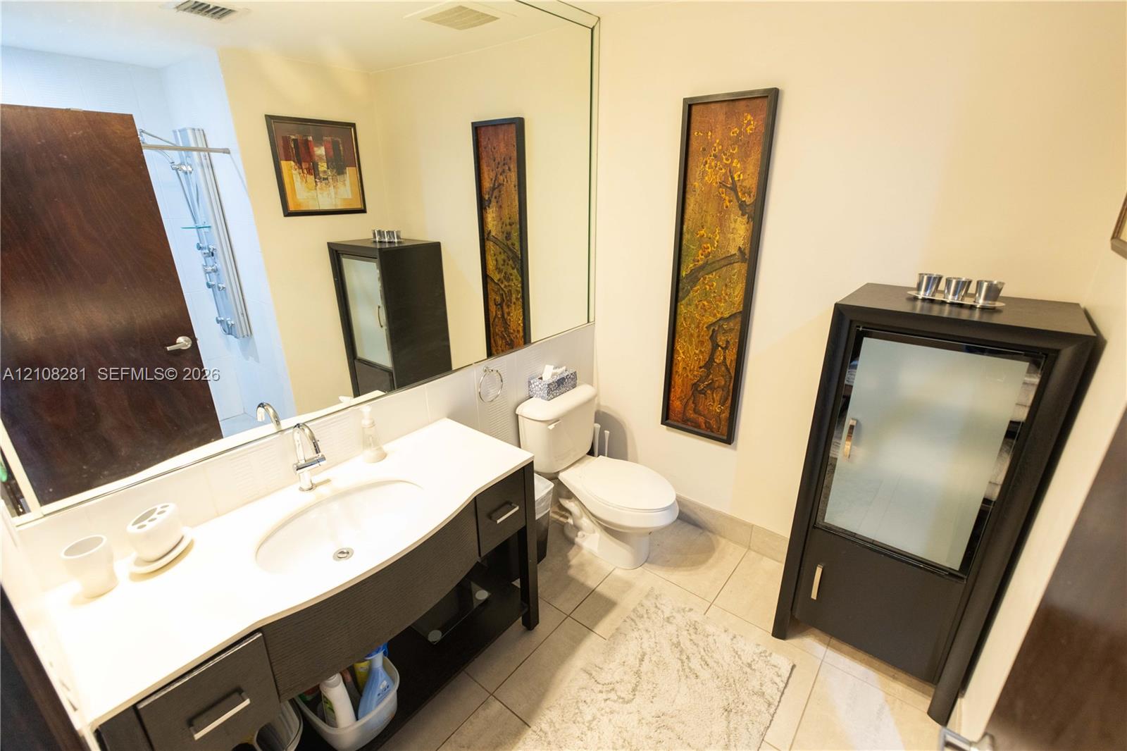 Bathroom featuring a vanity with a white countertop and oval under-mount sink, full-width wall mirror, and large-format tile flooring