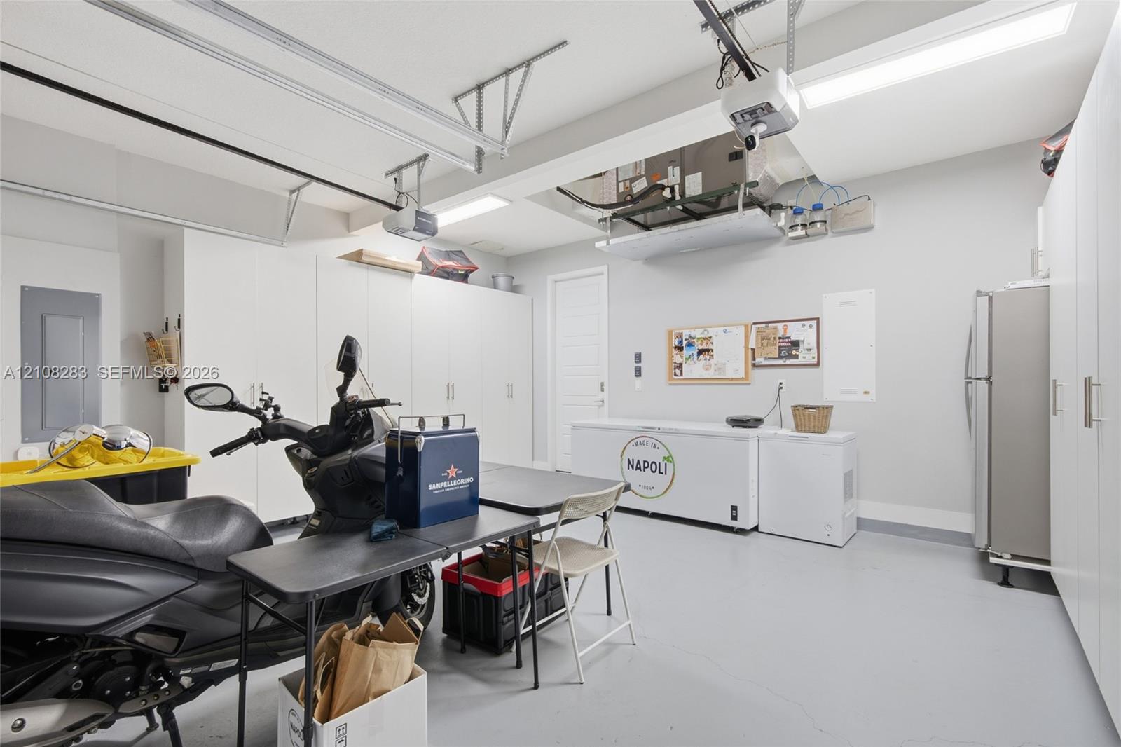 Garage space featuring extensive wall-to-wall built-in cabinetry, epoxy-finished flooring, and overhead lighting