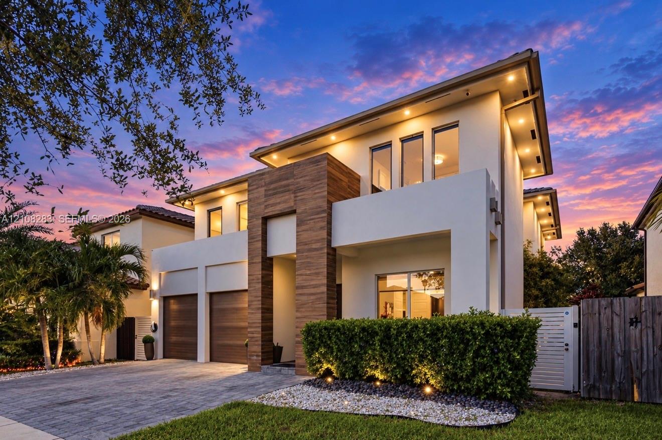 Contemporary exterior featuring smooth stucco finish, vertical wood-paneling accents, recessed soffit lighting, two-car garage with wood-finish doors, and paved driveway Contemporary exterior featuring smooth stucco finish, vertical wood-paneling accents, recessed soffit lighting, two-car garage with wood-finish doors, and paved driveway