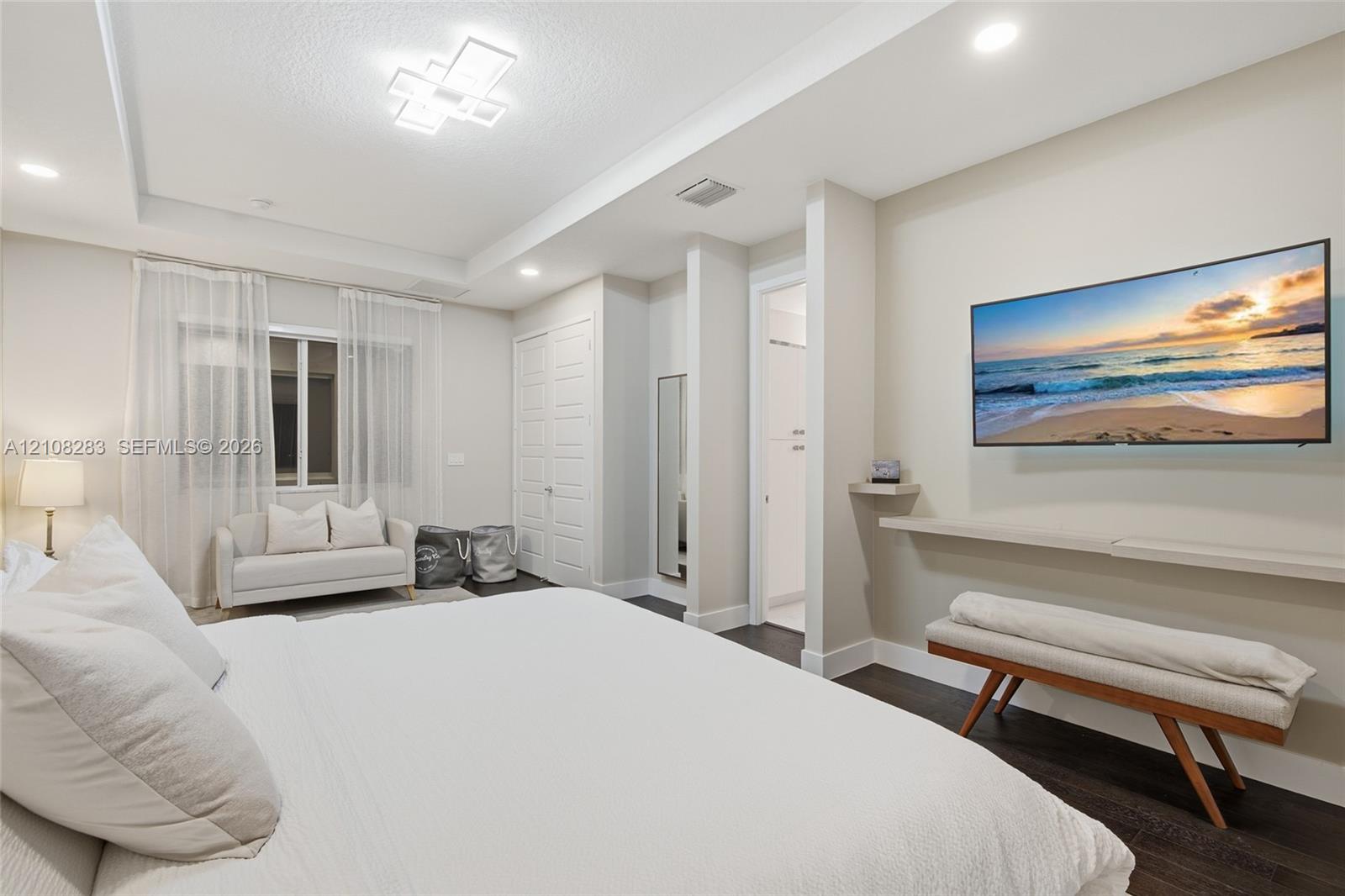 Tray ceiling with geometric flush-mount lighting, dark wood-finish flooring, recessed lighting, and a wall-mounted floating shelf