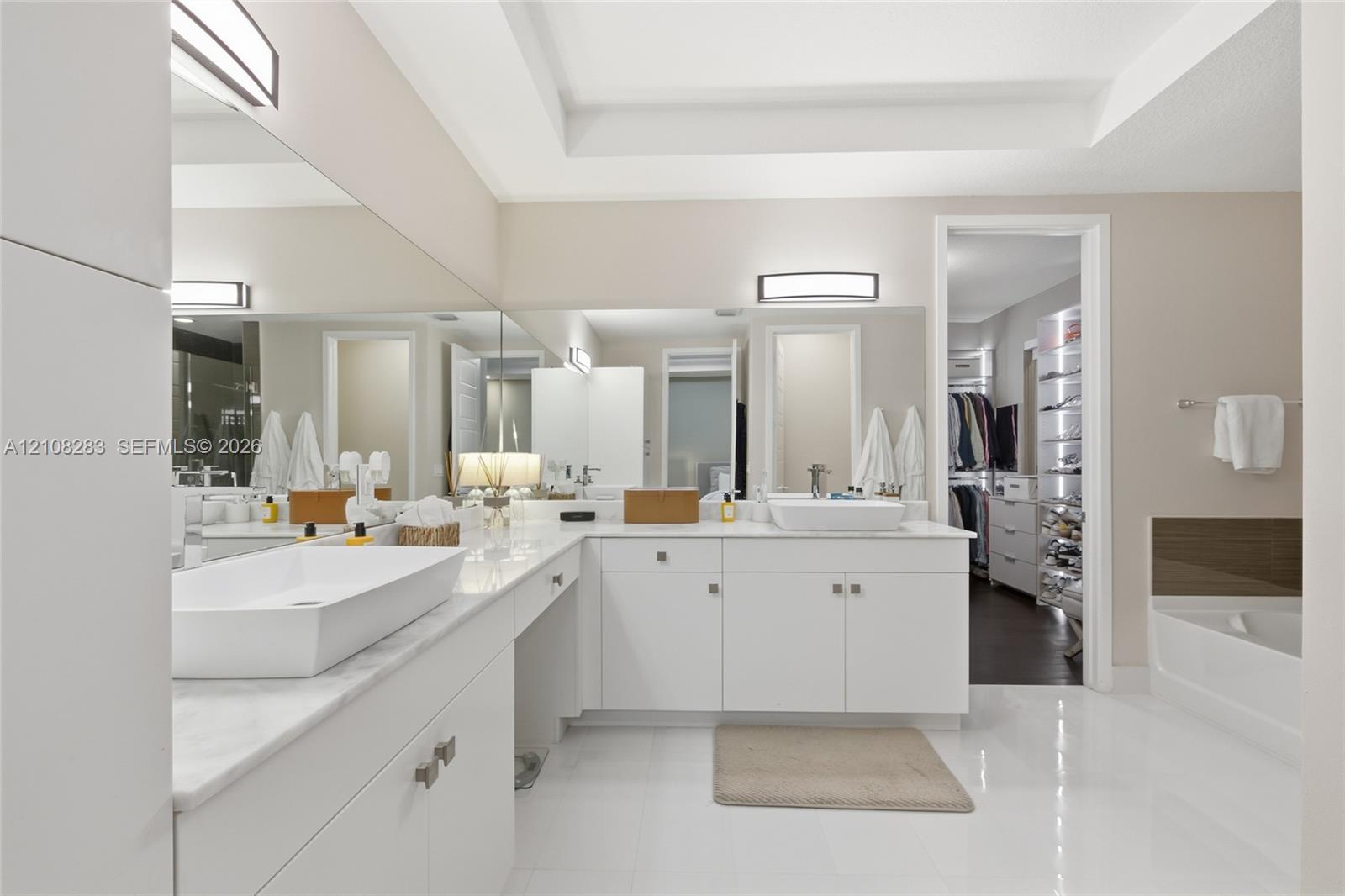 Dual vanity featuring rectangular vessel sinks, white stone countertops, white cabinetry with brushed metallic hardware, and full-width wall mirrors