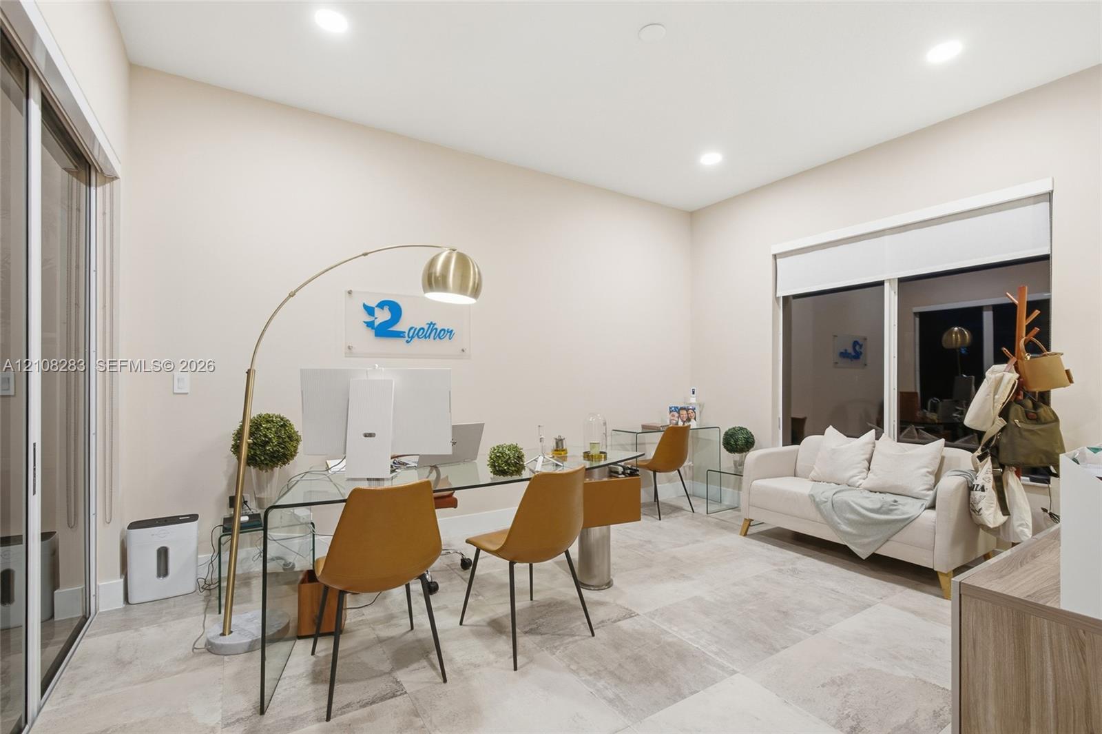 Neutral-toned room featuring large-format tile flooring, recessed ceiling lighting, and sliding glass doors with integrated roller shades