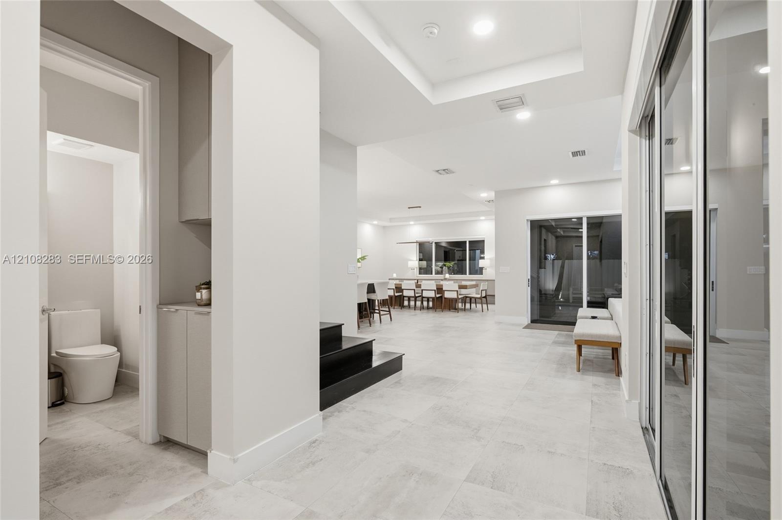 Interior space featuring large-format tile flooring, recessed ceiling lighting, tray ceilings, built-in cabinetry, and sliding glass doors