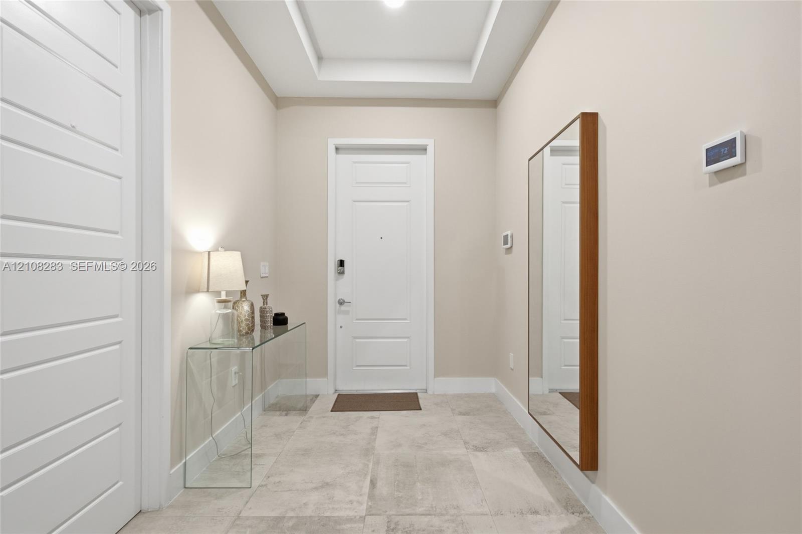 Entryway featuring large-format tile flooring, a tray ceiling, and a paneled entry door