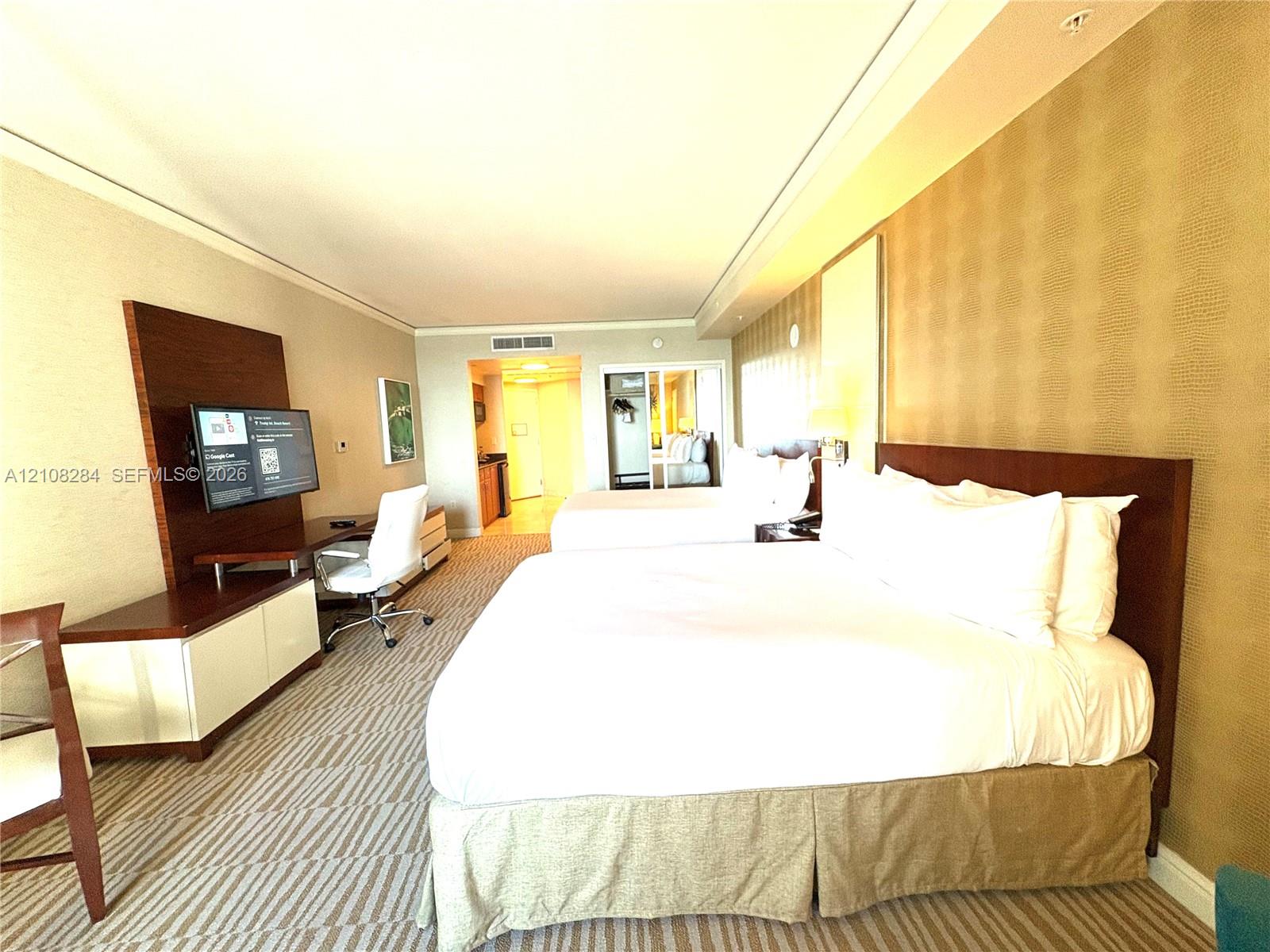 Spacious room featuring patterned carpeting, recessed ceiling lighting, textured wall coverings, and integrated media cabinetry with a built-in workspace
