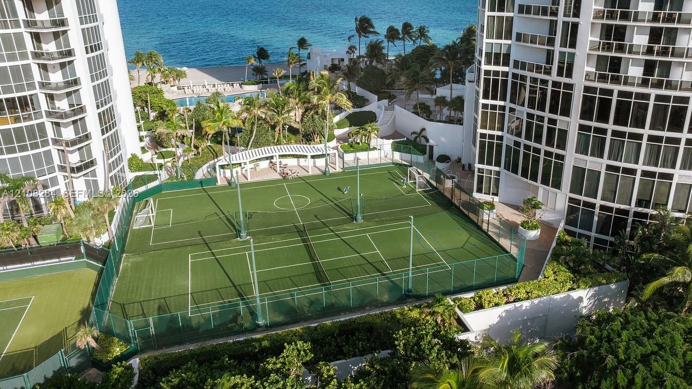 Multi-purpose athletic court featuring synthetic turf, perimeter fencing, and an integrated pergola