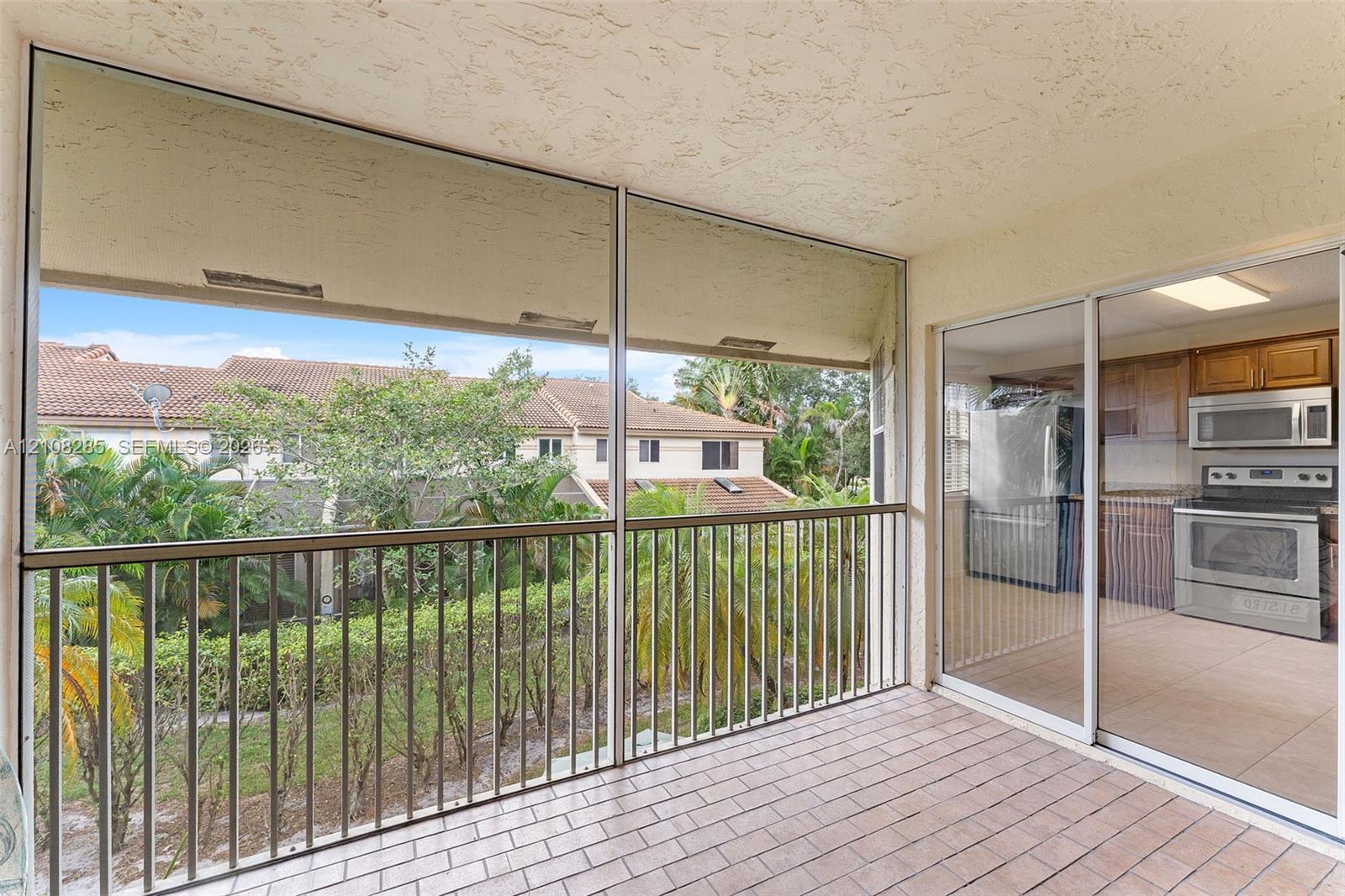Screened-in balcony featuring tile flooring, metal railings, and sliding glass entry doors