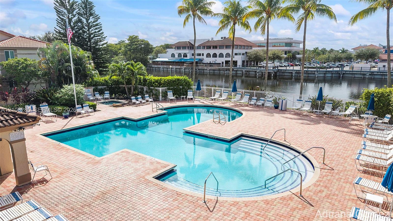 Swimming pool with integrated spa and stepped entry, surrounded by a brick paver deck and mature palm trees