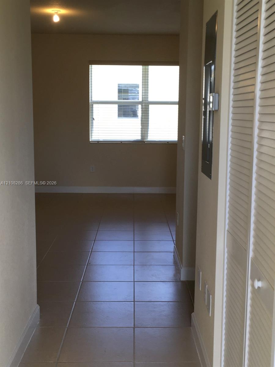 Interior space featuring large-format tile flooring, louvered bi-fold closet doors, and a multi-pane window with installed blinds