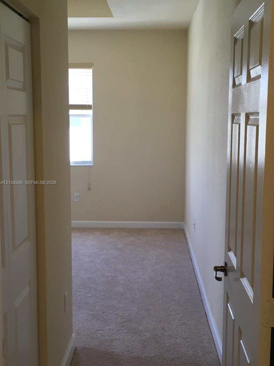 Neutral-toned room featuring neutral carpeting, a single-panel window with a blind, and six-panel interior doors
