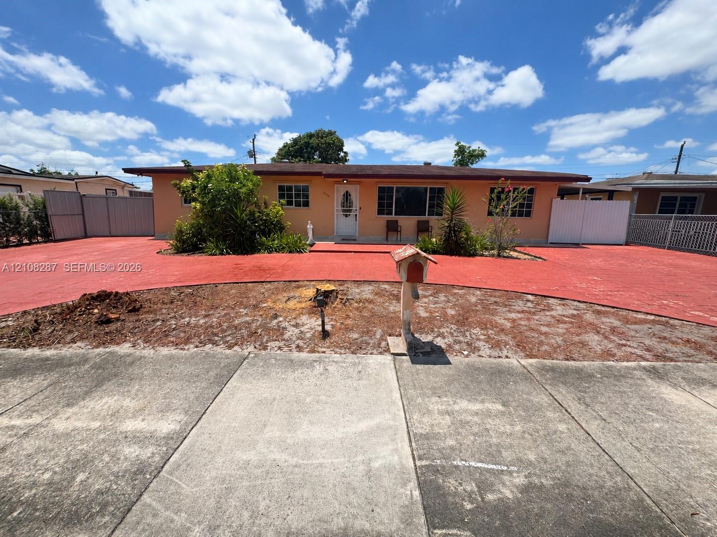 Single-story residence featuring an expansive paved driveway, white privacy fencing, and multi-pane windows