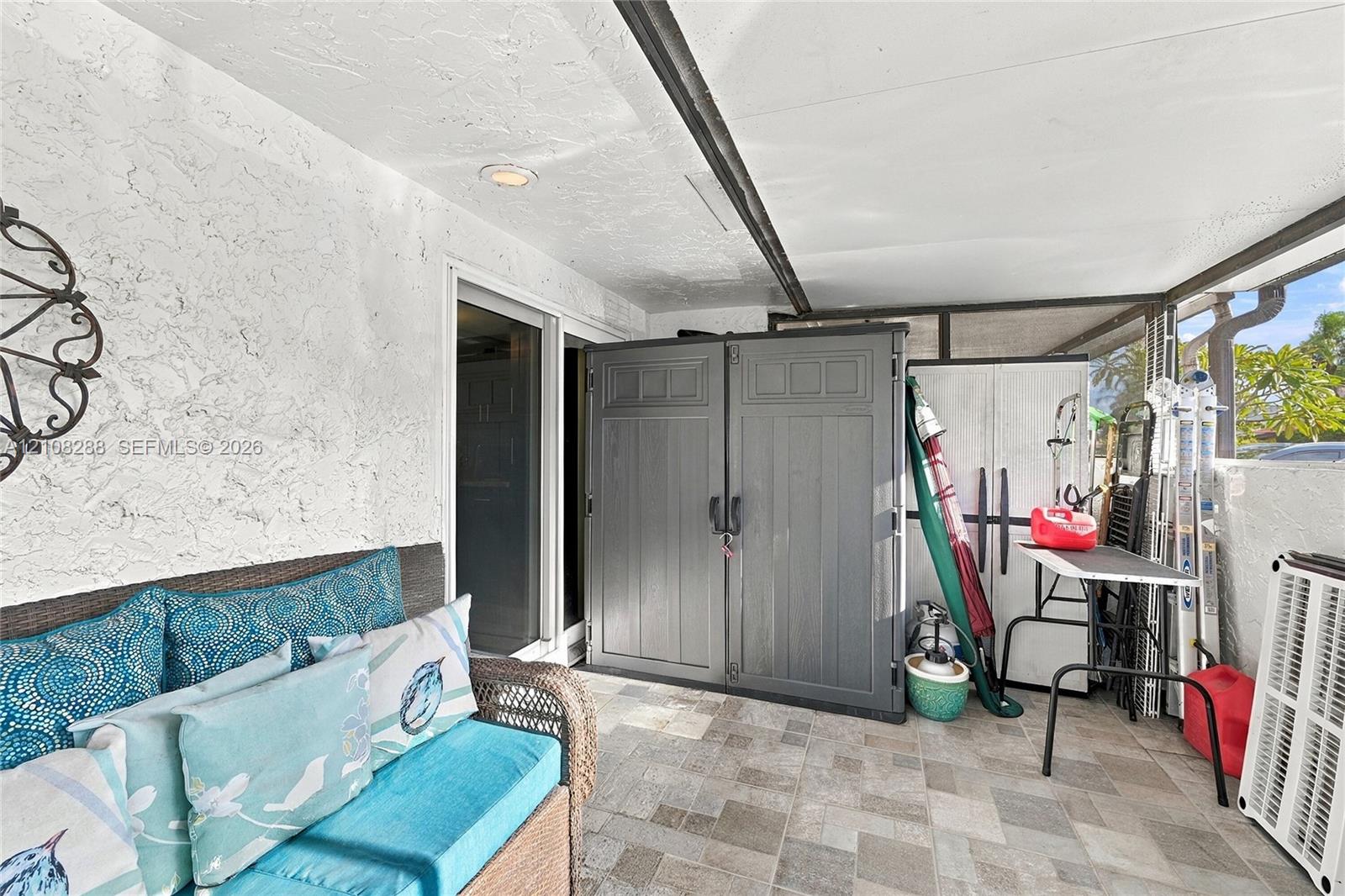Covered patio featuring textured walls, recessed lighting, and stone-finish tile flooring